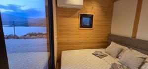 a bedroom with a bed with a view of a lake at Tiny Merak - Ramsko jezero in Kovačevo Polje