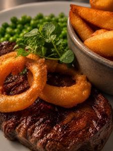 a plate of steak with onion rings and green peas at Whiston Hall in Whiston