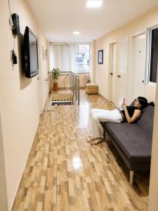 a woman sitting on a couch in a living room at Hostal Avanza in Cali