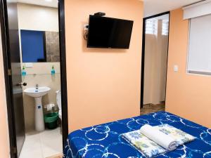 a bedroom with a bed with a tv on the wall at Hostal Avanza in Cali