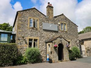 a stone building with a sign on top of it at Dales Retreat in Skipton