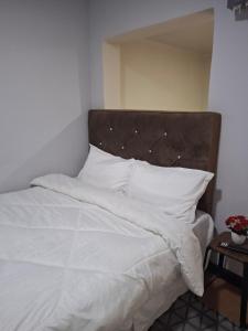 a bed with white sheets and pillows on it at Elimisam cabin in Kitwe