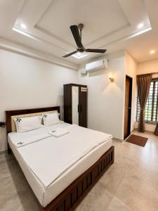 a bedroom with a large bed with a ceiling fan at Nakshatra Boarding and Lodging in Mangalore International