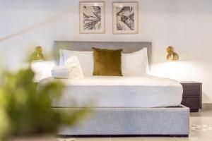 a bedroom with a bed with white sheets and gold pillows at Casa Las Ruinas Boutique Hotel in San Juan