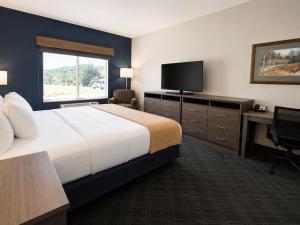 a hotel room with a bed and a desk and a television at Stay USA Hotel and Suites in Hot Springs