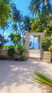 an open door to a beach with palm trees at Naraha Beach House in Kidenga