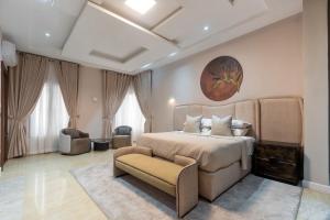 a bedroom with a large bed and a chair at Yaniv Apartments Oniru in Lagos