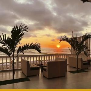 ein Balkon mit Sofas, Palmen und einem Sonnenuntergang in der Unterkunft Via marina in Same