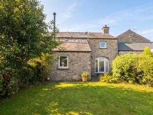 an exterior view of a stone house with a yard at The Spinney in Milnthorpe