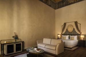 a bedroom with a bed and a couch and a table at Porta Rossa Hotel Firenze, Colbert Collection in Florence