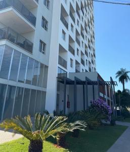 a white building with palm trees in front of it at Apartamento completamente equipado! Con Parking! En Paraná Playa Deptos! in Encarnación