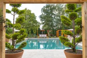 a swimming pool with two trees in front of a house at Bishopstrow Hotel and Spa - Small Luxury Hotels of the World in Warminster