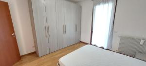 a white bedroom with a bed and a window at Mansuè, appartamento con giardino fra Oderzo e Pordenone in Mansuè
