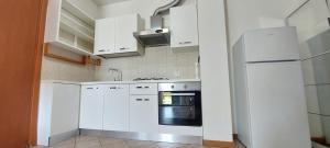 a white kitchen with white cabinets and an oven at Mansuè, appartamento con giardino fra Oderzo e Pordenone in Mansuè