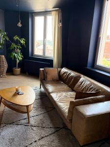 a living room with a brown leather couch and a table at Au pied du mur in Huy