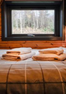 a bed with towels on it in front of a window at 1 Bedroom Cabin with Mountain & Loch Views - Quiet Location between Glencoe & Ben Nevis in Corran