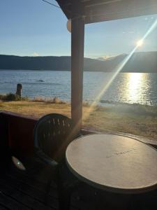 a table and chair on a porch with a view of the water at Longerak Camping in Bygland
