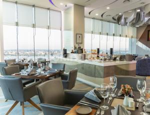 a restaurant with tables and chairs and large windows at HS HOTSSON Hotel Irapuato in Irapuato