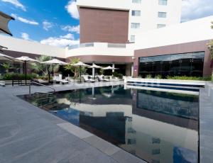 a swimming pool in front of a building at HS HOTSSON Hotel Irapuato in Irapuato