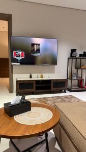 ein Wohnzimmer mit einem Tisch und einem Flachbildfernseher in der Unterkunft هاوس تو 21 in Abha