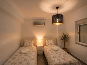 a bedroom with two beds and a pendant light at ENJOY POOL, BEACH and more at this nice 2bedroom apartment only 3 minutes from Mareta's Beach in Sagres +9 photos