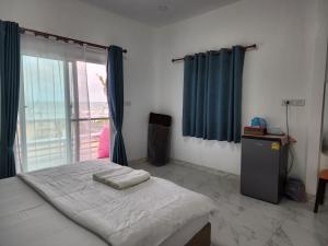 a bedroom with a bed with blue curtains and a window at Chomlay House in Ban Thepha +37 photos