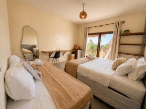 a bedroom with two beds and a mirror and a table at The Wave Kite House in Guriú +23 photos