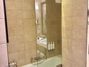 Eine Dusche mit Glastür neben einem Waschbecken in der Unterkunft Hotel Rotary Geneva - MGallery in Genf