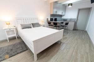 a bedroom with a large white bed and a kitchen at Casa do Foral by Lethes Legacy in Ponte de Lima