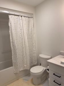 a bathroom with a toilet and a shower curtain at Modern Riverview Suite Near Downtown Moncton in Riverview +15 photos
