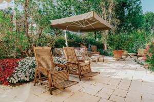 a patio with chairs and an umbrella and flowers at Hotel Miramare in Forte dei Marmi