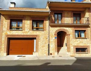 a brick house with two garage doors and a balcony at La Casona De Cuellar in Cuéllar