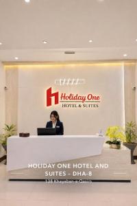 a woman sitting at a reception desk in a hotel at Holiday One Hotel & Suites - DHA-8 in Karachi