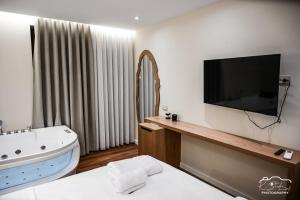 a bathroom with a tv and a bath tub and a bed at Rubin Boutique in Korçë