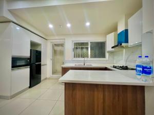 a kitchen with white counters and a black refrigerator at SkyPark Premium Hotel Serviced Apartments - LMY Hospitality Gulberg Islamabad in Islamabad