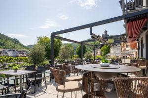 eine Terrasse mit Tischen und Stühlen auf einem Balkon in der Unterkunft Hotel La Baia in Cochem