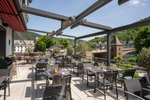 eine Terrasse in einem Restaurant mit Tischen und Stühlen in der Unterkunft Hotel La Baia in Cochem