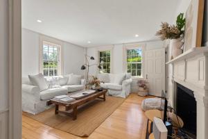 a living room with white furniture and a fireplace at Featured in Cape Cod Life Magazine in Barnstable