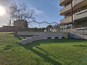 a fence in front of a building with a grass yard at Altea Suites in Pomezia
