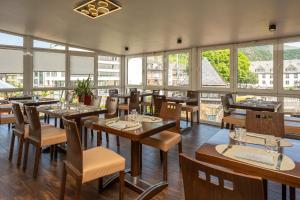 ein Restaurant mit Holztischen und -stühlen und Fenstern in der Unterkunft Hotel La Baia in Cochem