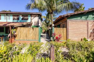 a house with a fence and a palm tree at Pousada Lua Chalés in Maresias