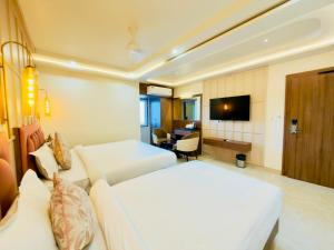 a hotel room with two beds and a desk at Hotel Sanidhyam Bliss in Varanasi
