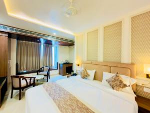 a hotel room with a large bed and a table at Hotel Sanidhyam Bliss in Varanasi