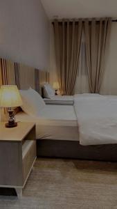 a bedroom with a large bed and a table with a lamp at فندق أوريون orion hotel in Al-ʿUla