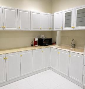 a white kitchen with white cabinets and a microwave at فيلا وشاليه الجبل الاحمر in Al-ʿUla