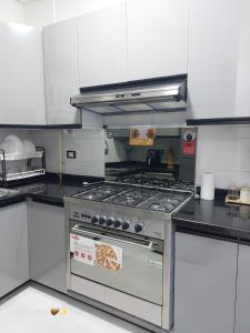 a kitchen with a stove with a pizza on it at Royal Green Haven 3BR Apartment near Airport Obour in Obour