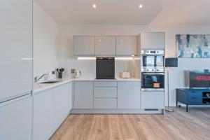 a white kitchen with white cabinets and appliances at Thameside Suite | Free Parking | 2 BR | Heathrow in Staines +19 photos