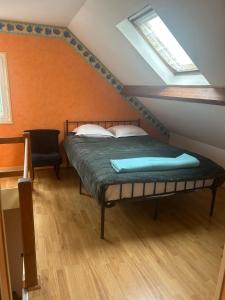 a bedroom with a bed and a chair in a attic at une détente à la campagne in Chierry