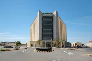 a large building with a parking lot in front of it at Acacia Hotel Ras Al Khaimah by AMR in Ras al Khaimah