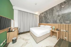 a hotel room with a bed and a television at Acacia Hotel Ras Al Khaimah by AMR in Ras al Khaimah